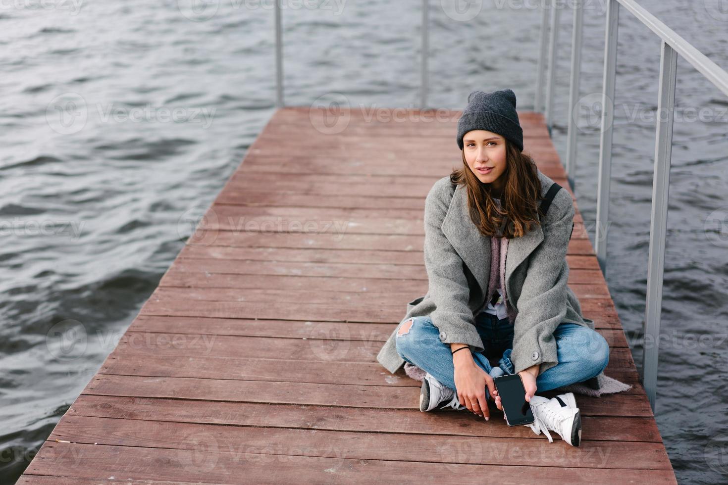 jeune jolie fille sur un banc en bois sur l'ancienne jetée photo