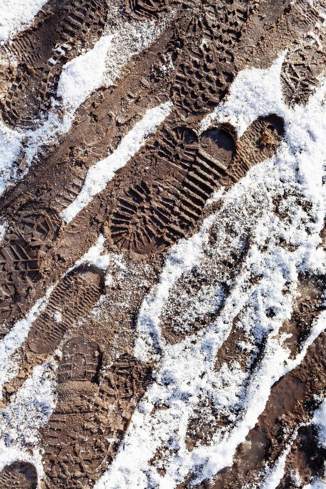 empreintes de pas sur un chemin sale recouvert de neige photo