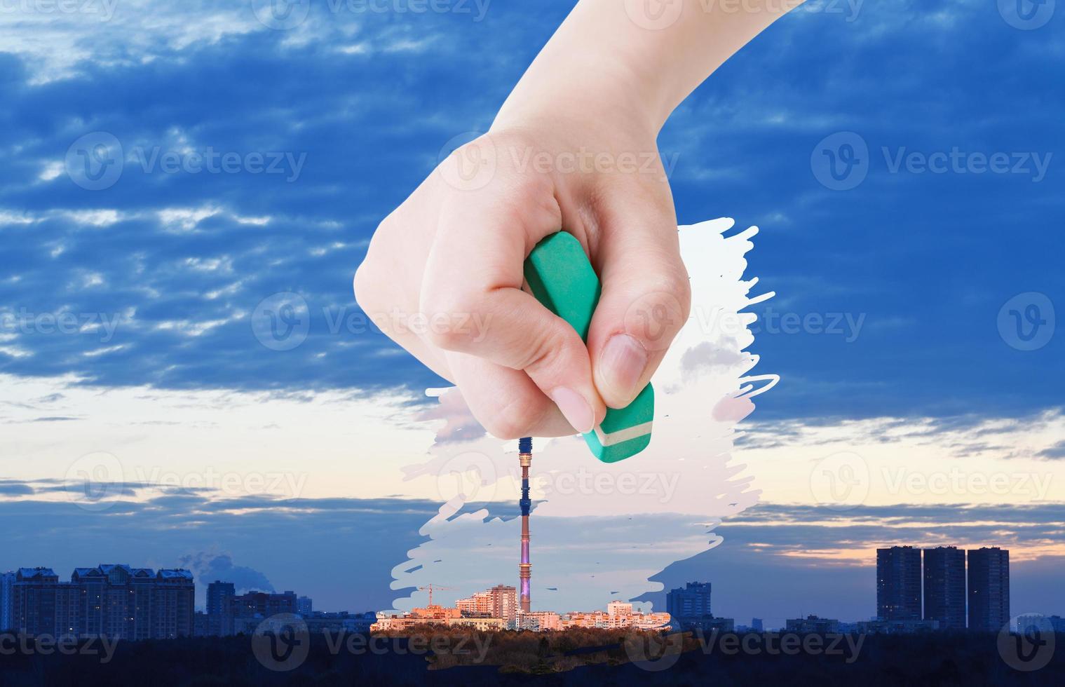 la main supprime le lever du soleil sur la ville par une gomme en caoutchouc photo