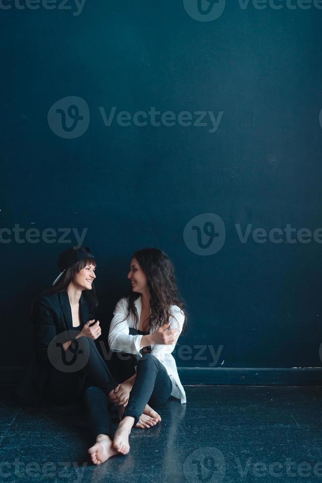 de belles filles s'assoient près du mur et posent photo