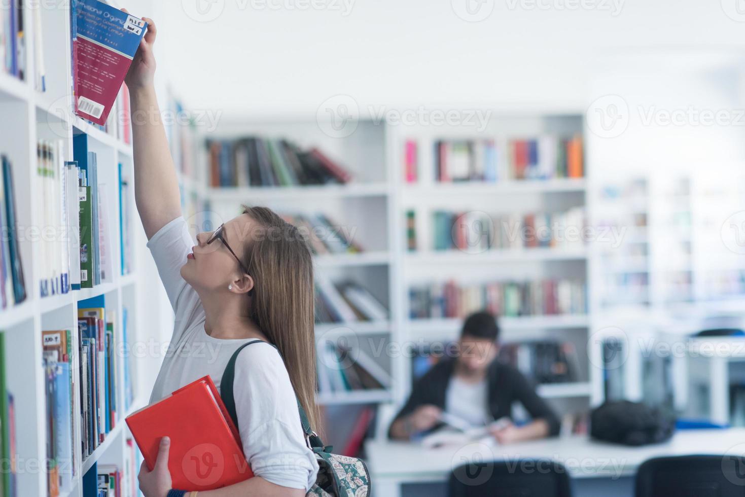 étudiante célèbre en sélectionnant un livre à lire dans la bibliothèque photo