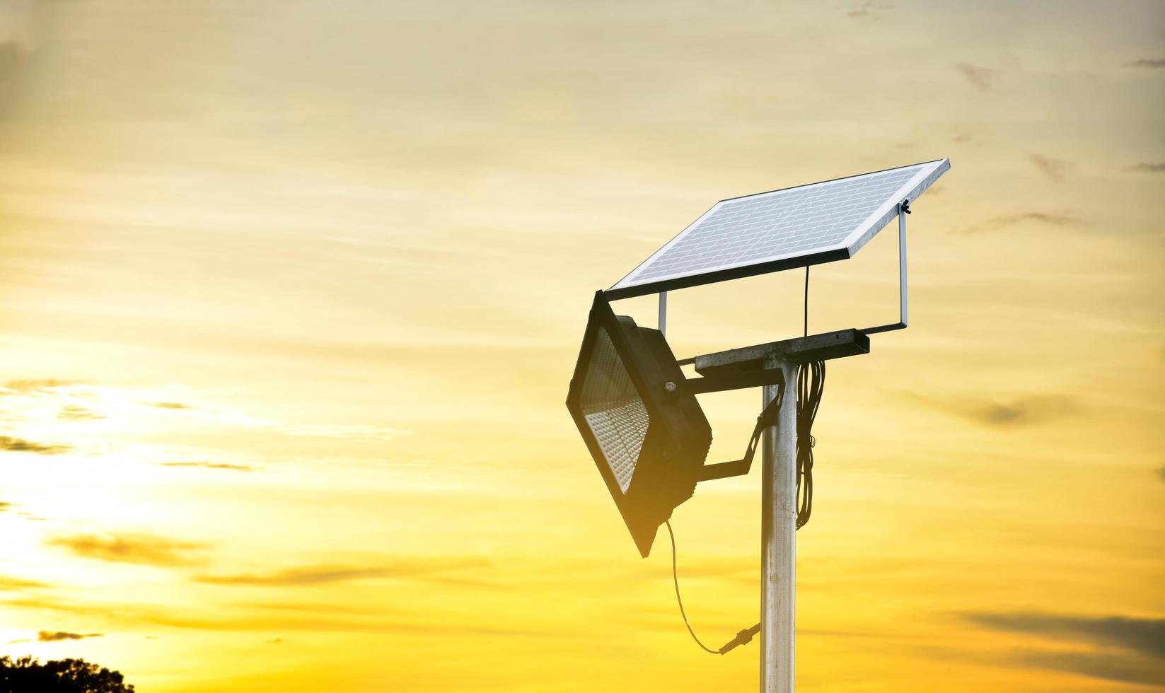 mini panneau de cellules solaires ou photovoltaïques installé sur un poteau métallique avec projecteur led, arrière-plan flou nuageux et bluesky, concept d'utilisation de l'énergie naturelle du soleil dans la vie quotidienne de l'homme. photo