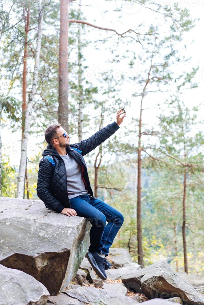 un gars est assis dans les bois sur un rocher photo