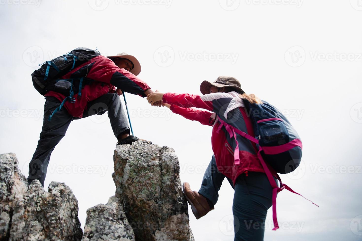 une personne fait de la randonnée avec des amis qui s'entraident sur une montagne. homme et femme donnant un coup de main et mode de vie actif. un couple d'asie en randonnée s'entraide. concept d'amitié, travail d'équipe. photo