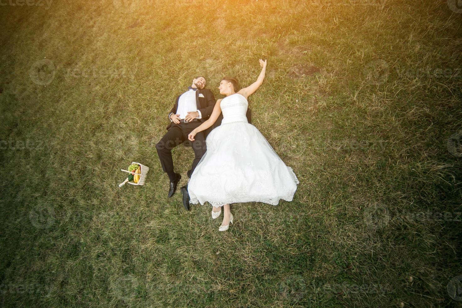 couple de mariés allongé sur l'herbe photo