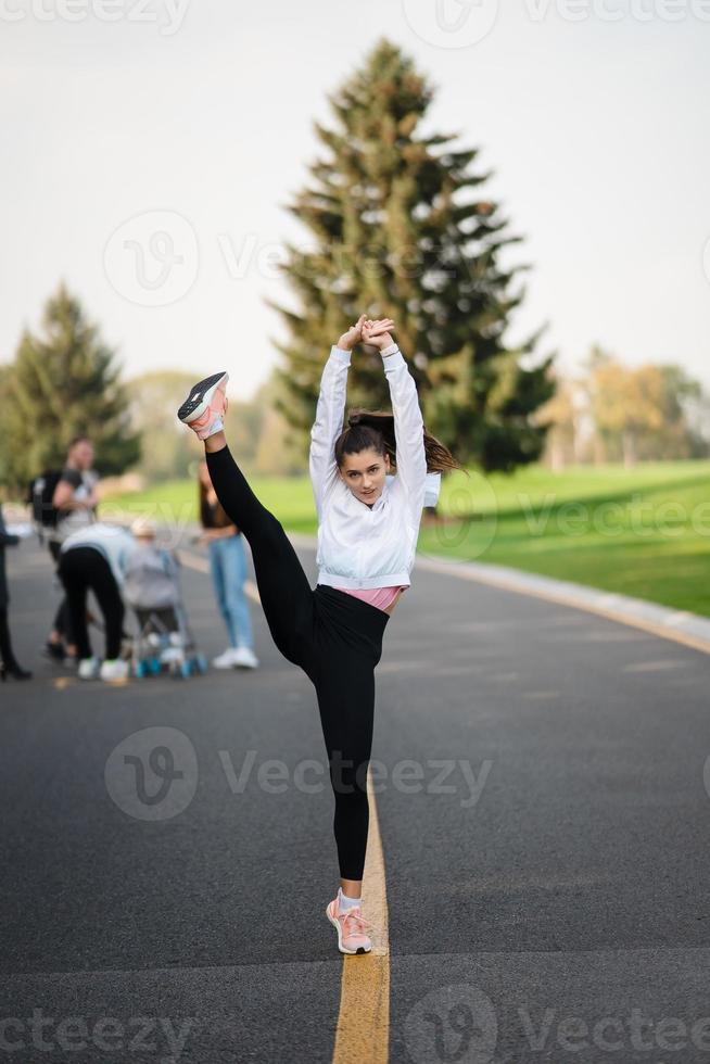 femme en tenue de sport sur la route faisant des divisions debout. photo