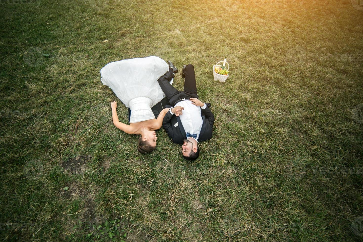 couple de mariés allongé sur l'herbe photo