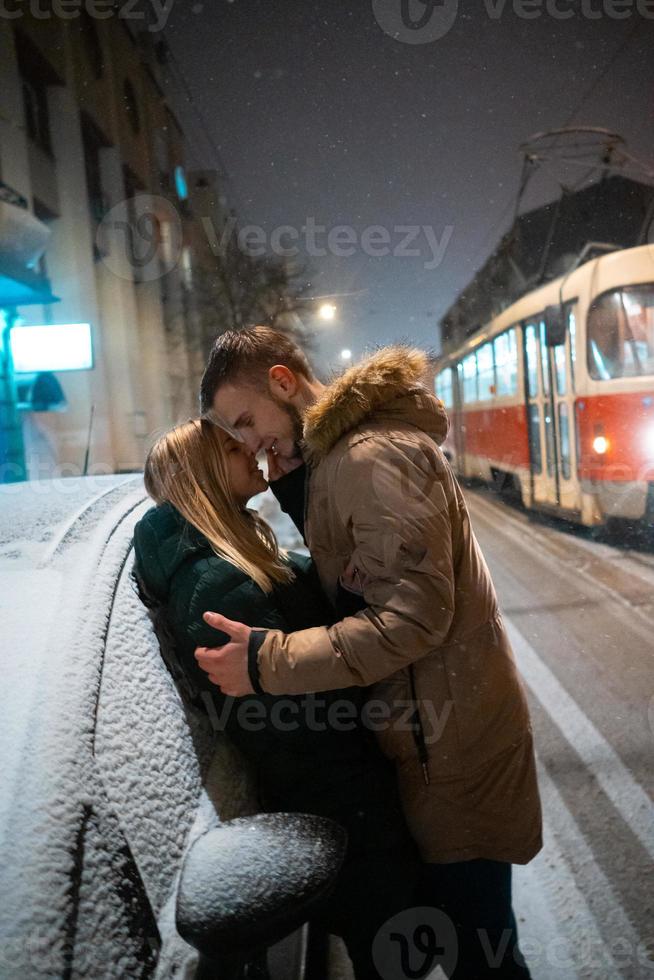 jeune couple adulte s'embrassant sur la rue couverte de neige photo