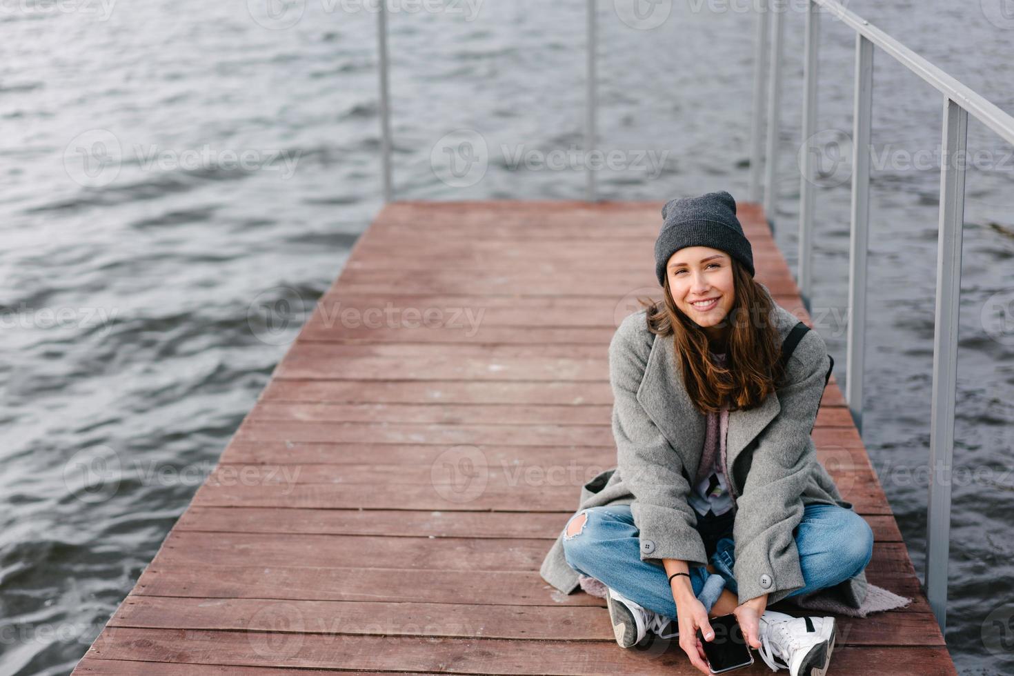 jeune jolie fille sur un banc en bois sur l'ancienne jetée photo