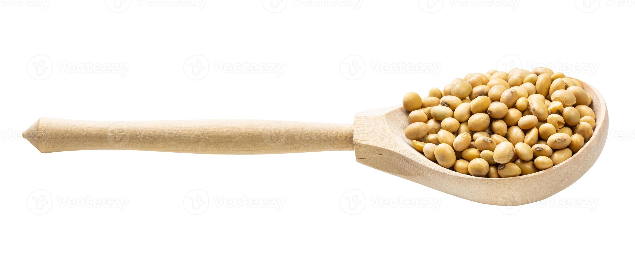 cuillère en bois avec des graines de soja séchées crues isolées photo