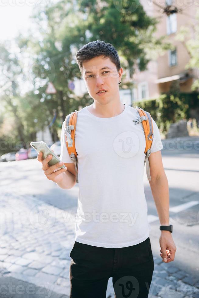 portrait d'un jeune homme touchant un écran mobile dans la rue photo