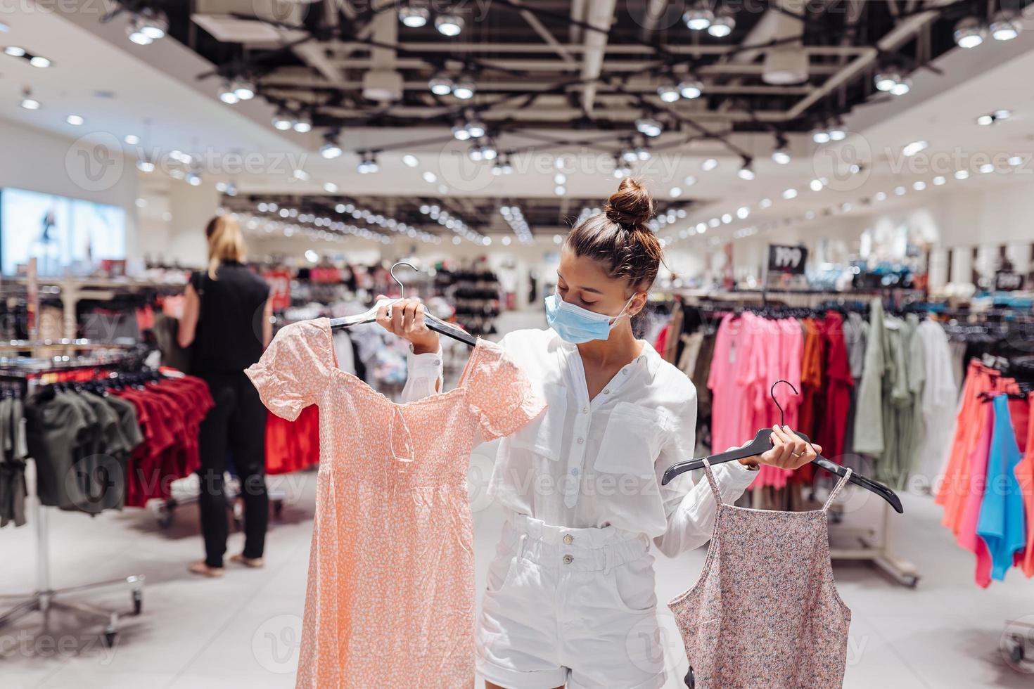jeune femme faisant du shopping dans une boutique de vêtements avec masque de protection photo