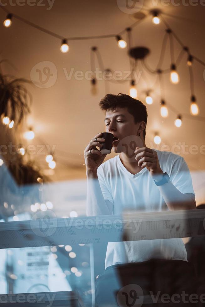 jeune et bel homme boit son café du matin dans un café. photo