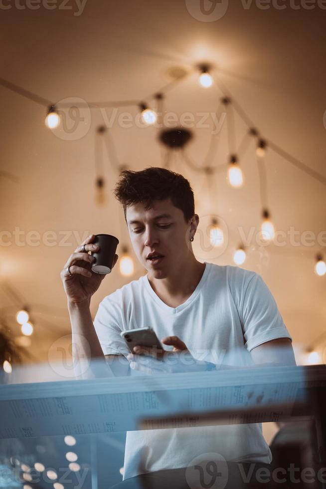 jeune et bel homme boit son café du matin dans un café. photo