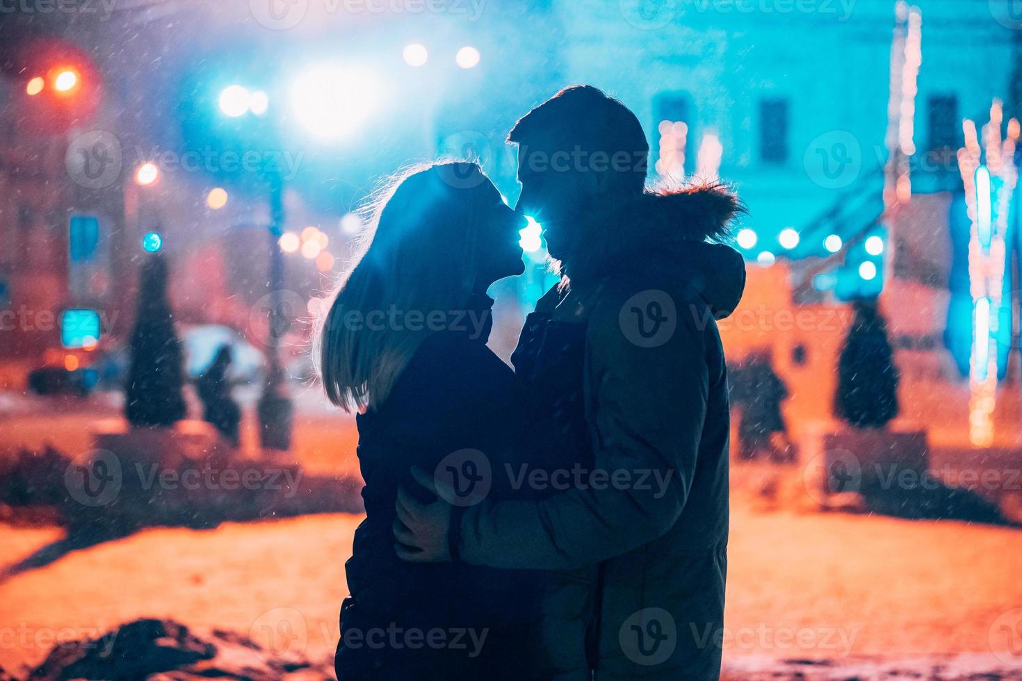 jeune couple adulte dans les bras l'un de l'autre sur la rue couverte de neige. photo