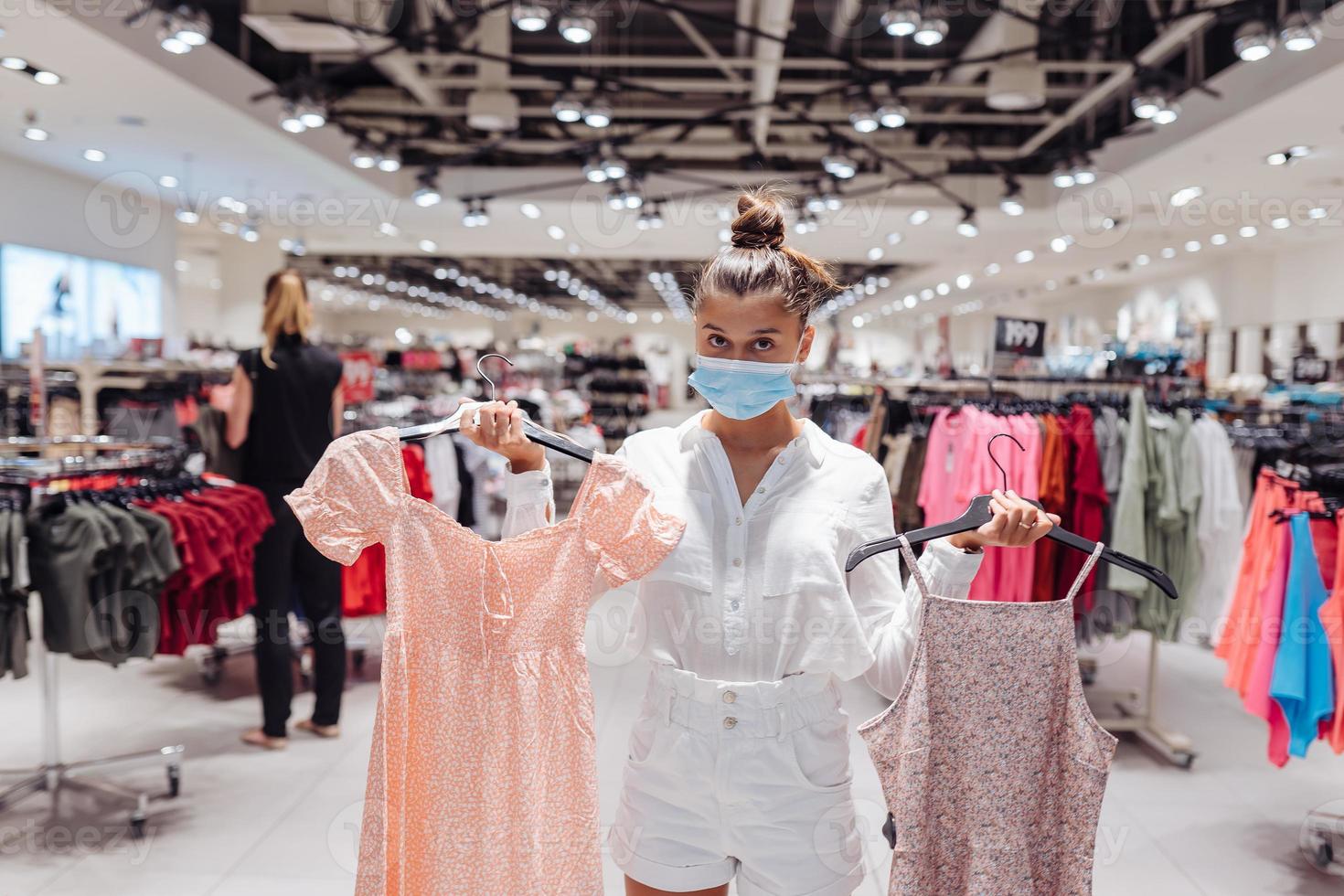 jeune femme faisant du shopping dans une boutique de vêtements avec masque de protection photo