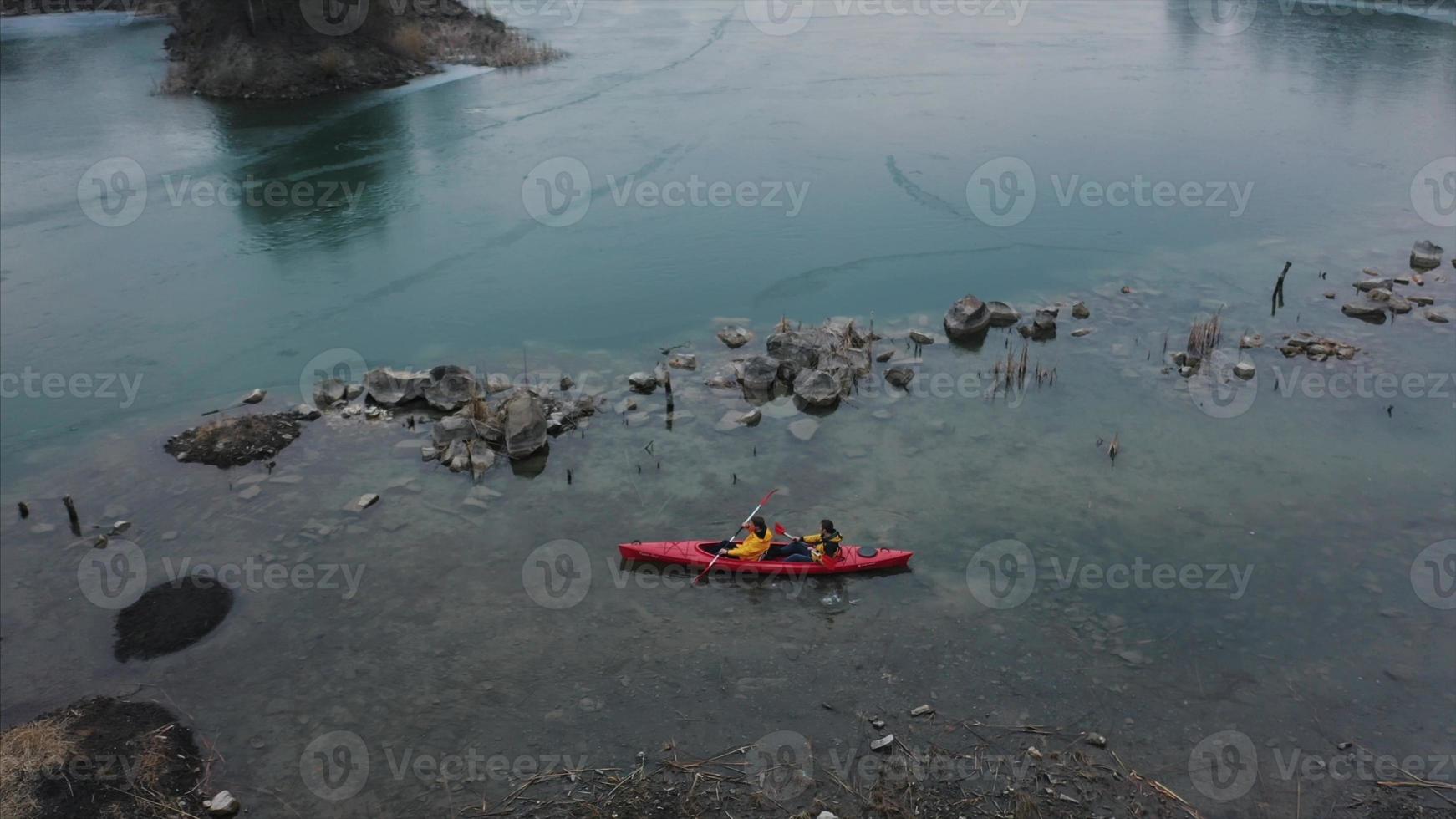 deux hommes athlétiques flottent sur un bateau rouge dans la rivière photo