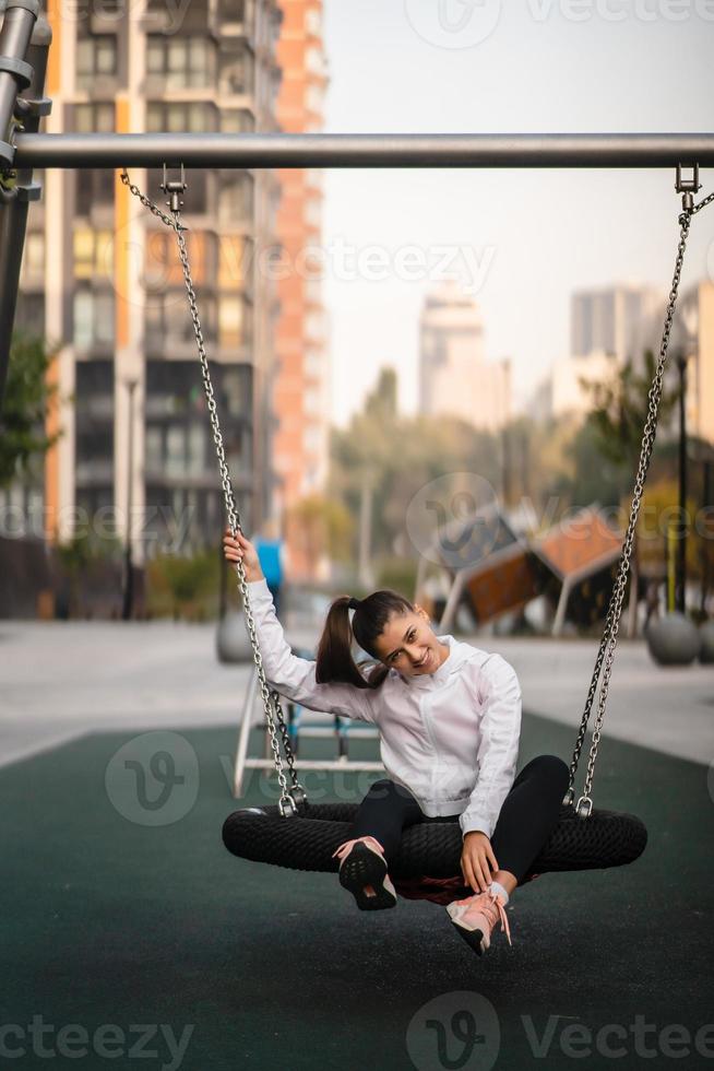 jeune femme monte sur une balançoire à l'aire de jeux. photo