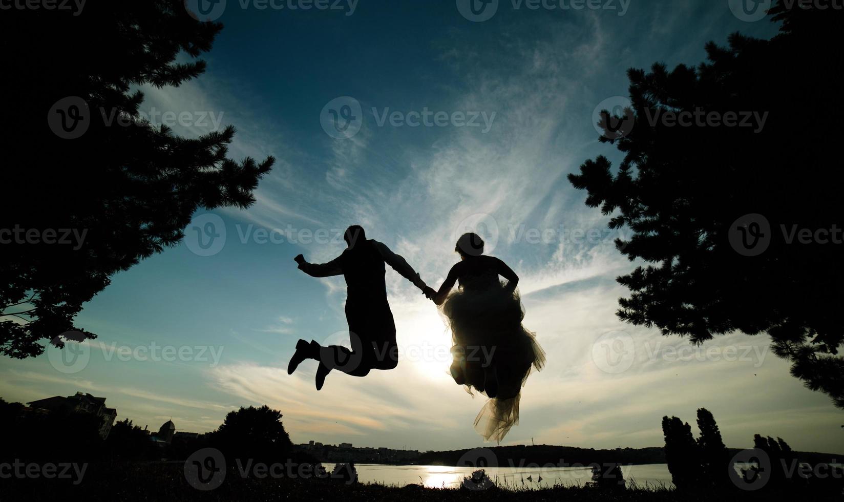 marié et mariée sautant contre le beau ciel photo