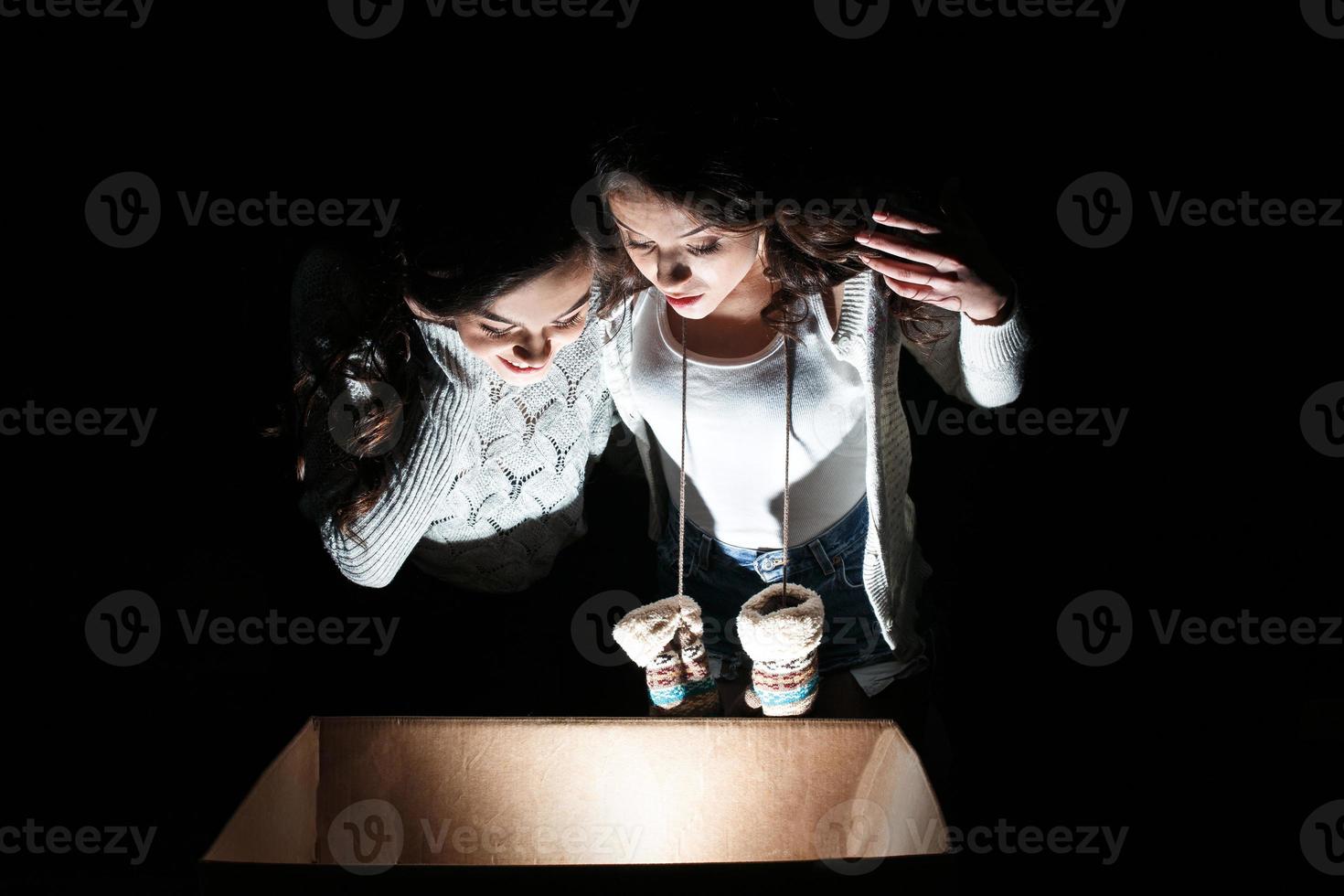 les soeurs ouvrent une boîte avec un cadeau de noël et des regards fascinés à l'intérieur photo