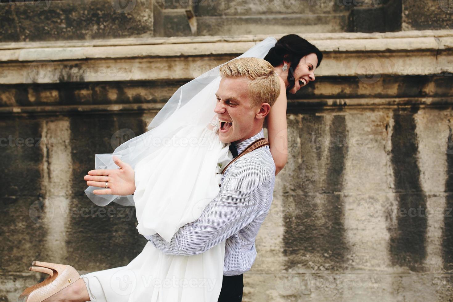 le marié porte la mariée dans ses bras photo