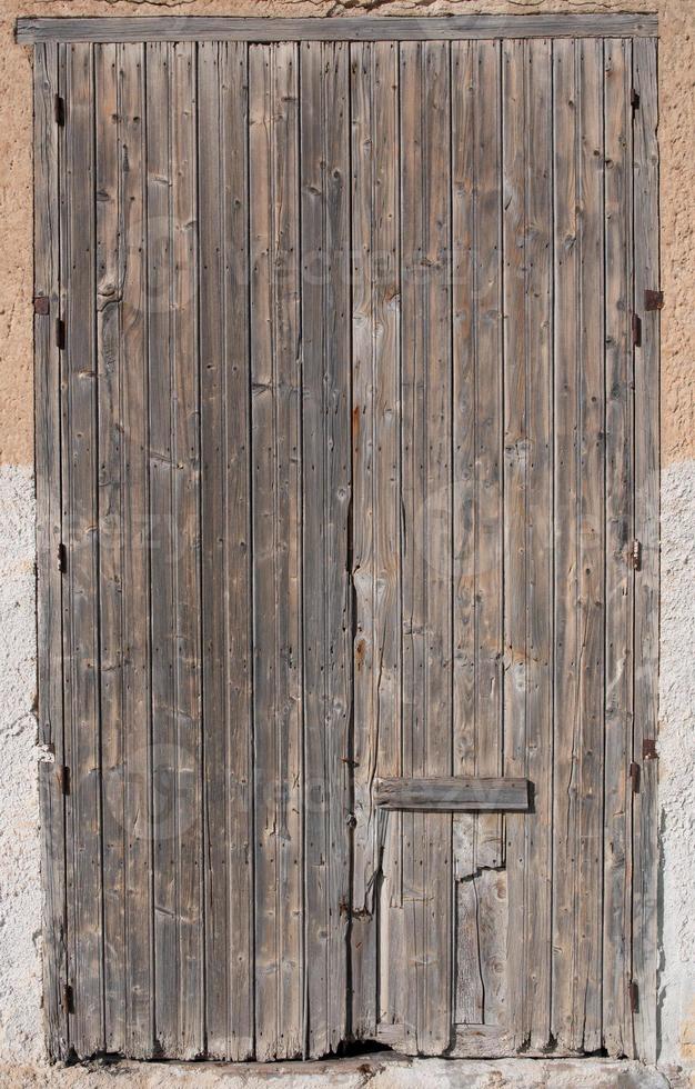 arrière-plan d'une vieille porte en bois fermée et patinée qui est au format portrait dans un vieux mur. photo