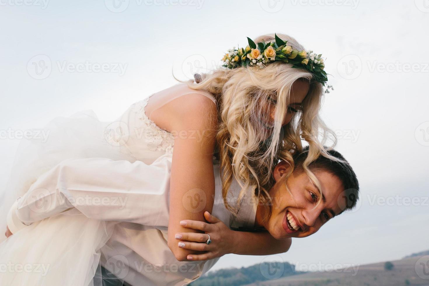 le marié porte la mariée sur son dos à l'extérieur photo