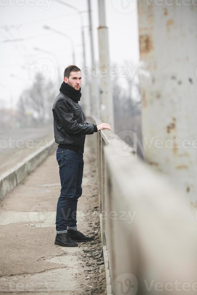 un homme vêtu d'un jean et d'une veste se tient près de la route principale par temps de brouillard photo