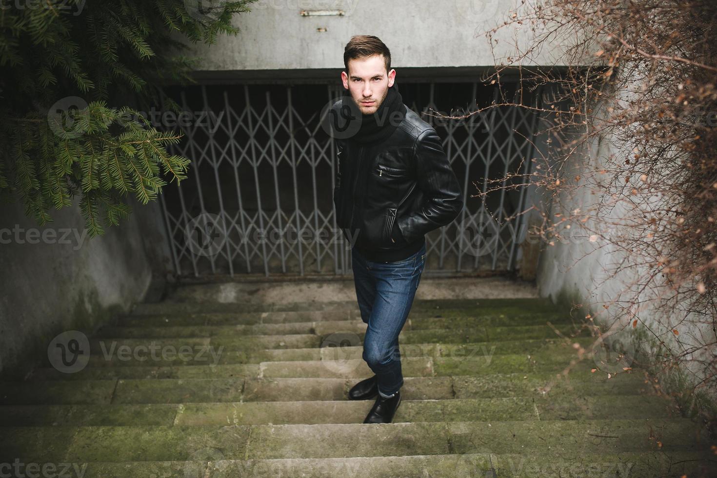 un homme vêtu d'un jean et d'une veste noire sur des escaliers authentiques photo