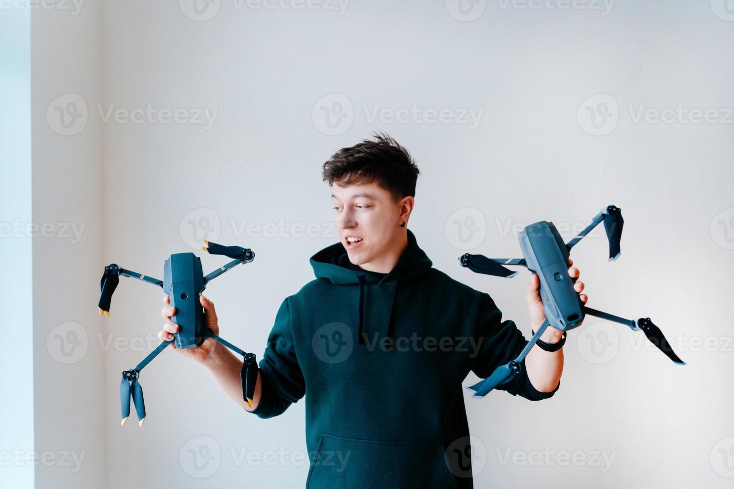 un gars tient deux quadricoptères contre un mur photo