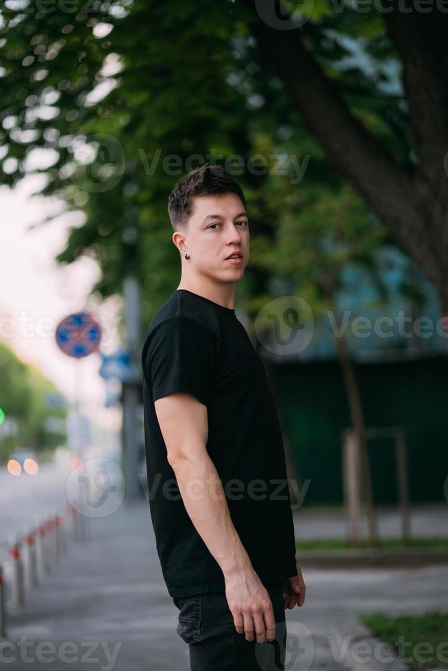 jeune homme adulte dans un t-shirt noir et un jean marche dans une rue de la ville photo