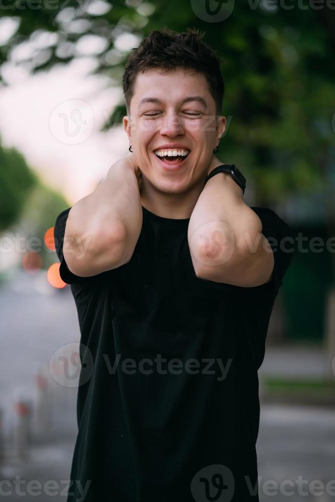 jeune homme adulte dans un t-shirt noir et un jean marche dans une rue de la ville photo