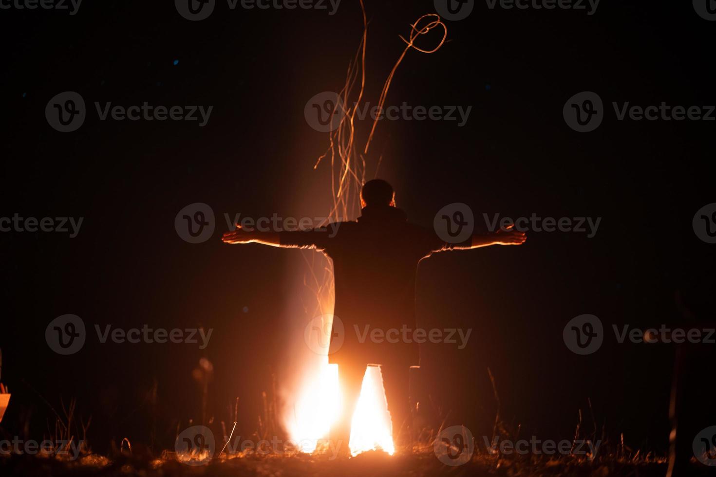 un homme se tient devant un feu à bras ouverts photo