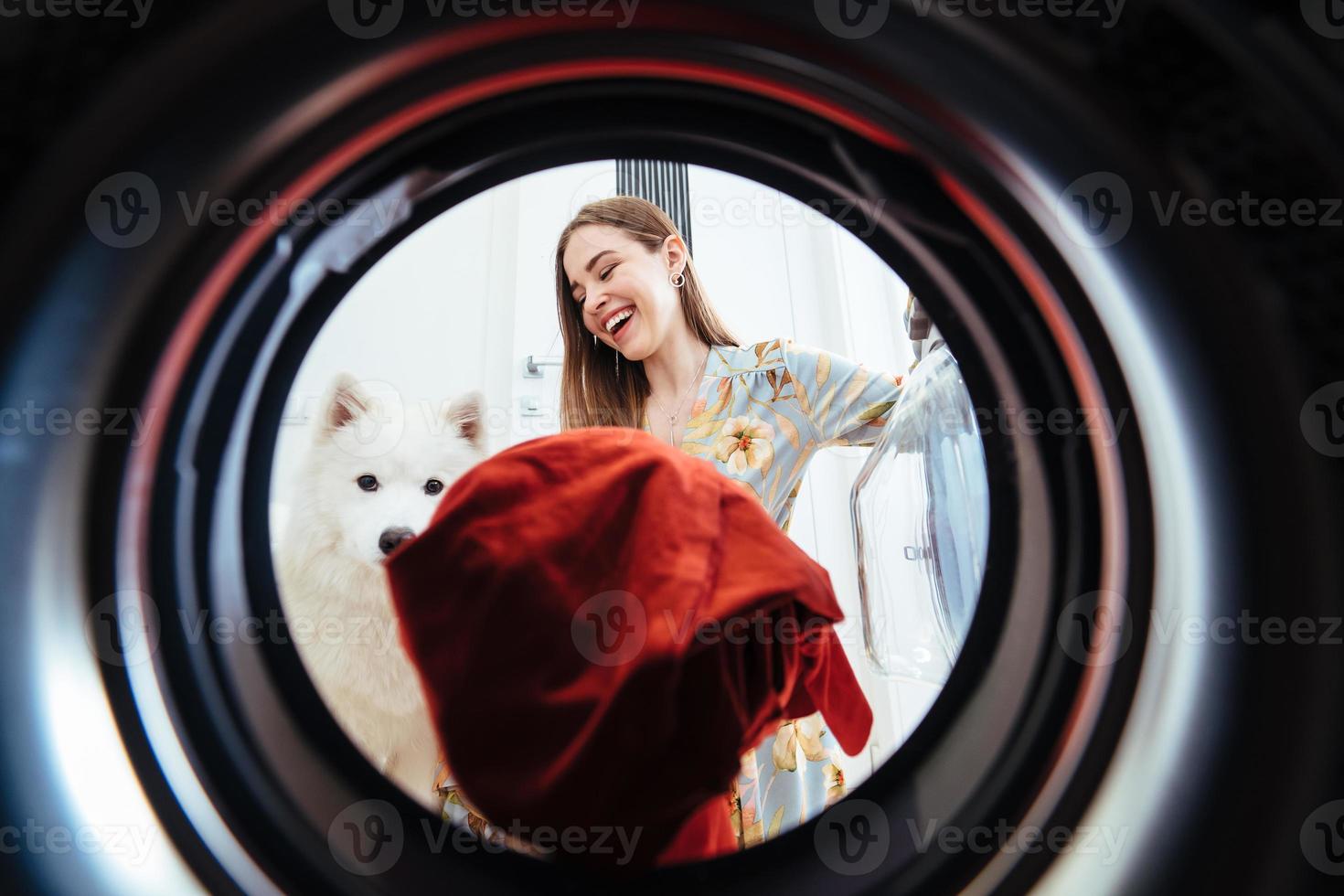 jeune femme à la maison met la robe dans la machine à sécher. photo