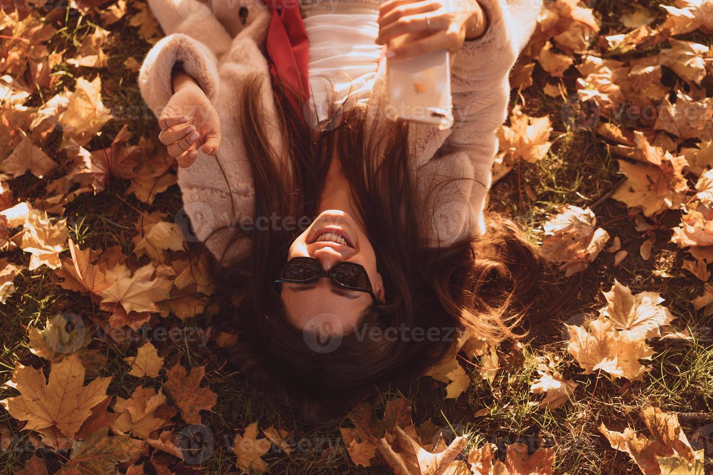 vue de dessus de la belle jeune femme se trouve sur les feuilles d'automne photo