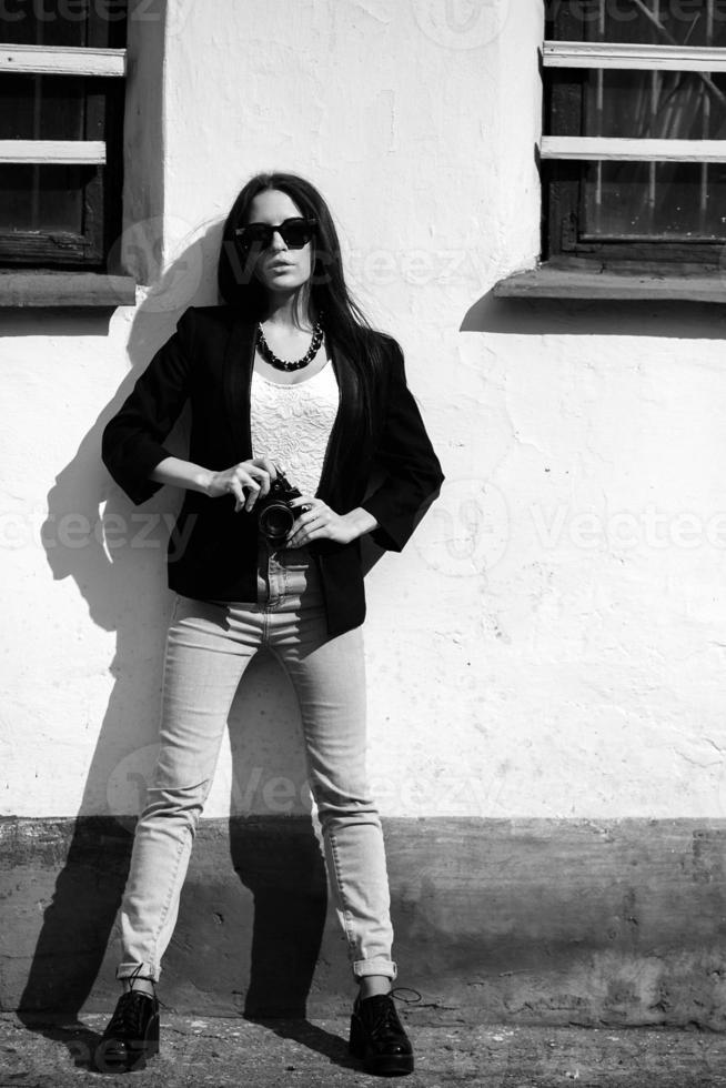 belle fille debout contre un mur avec un appareil photo