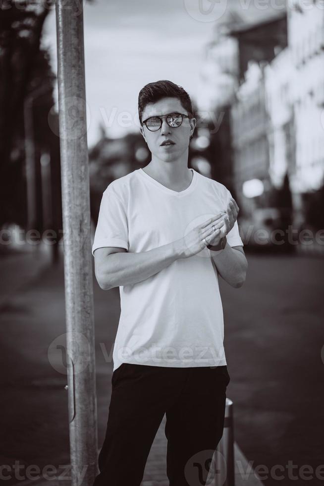 un gars se tient dans la rue de la ville, regarde la caméra et autour photo