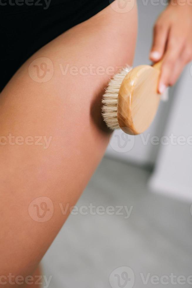 fille caressant sa jambe avec une brosse dans la salle de bain photo