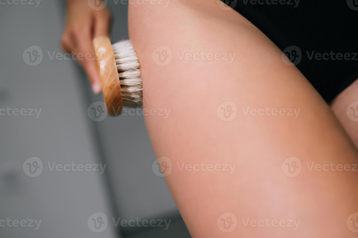 fille caressant sa jambe avec une brosse dans la salle de bain photo