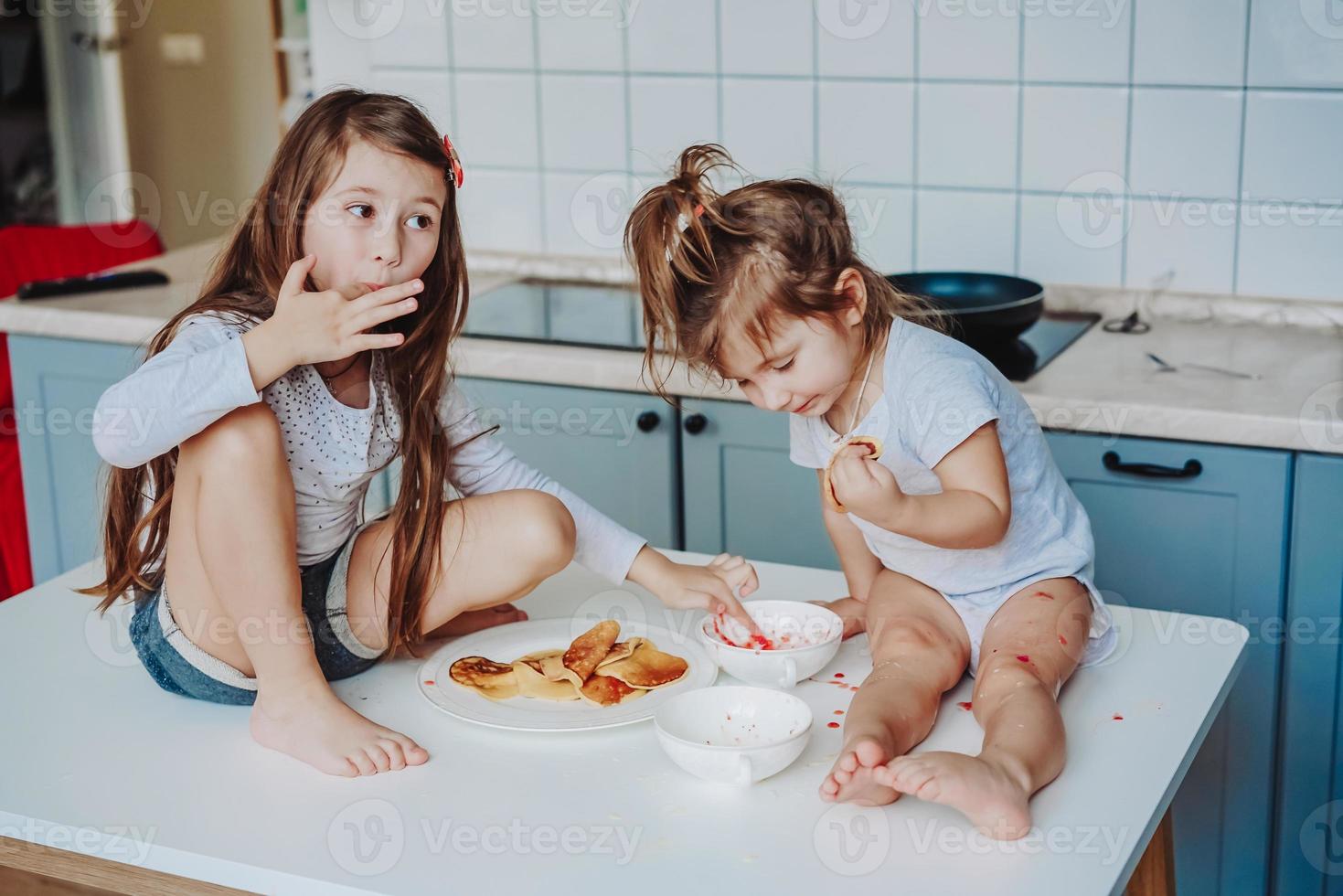 deux petites filles dans la cuisine assises sur la table. photo