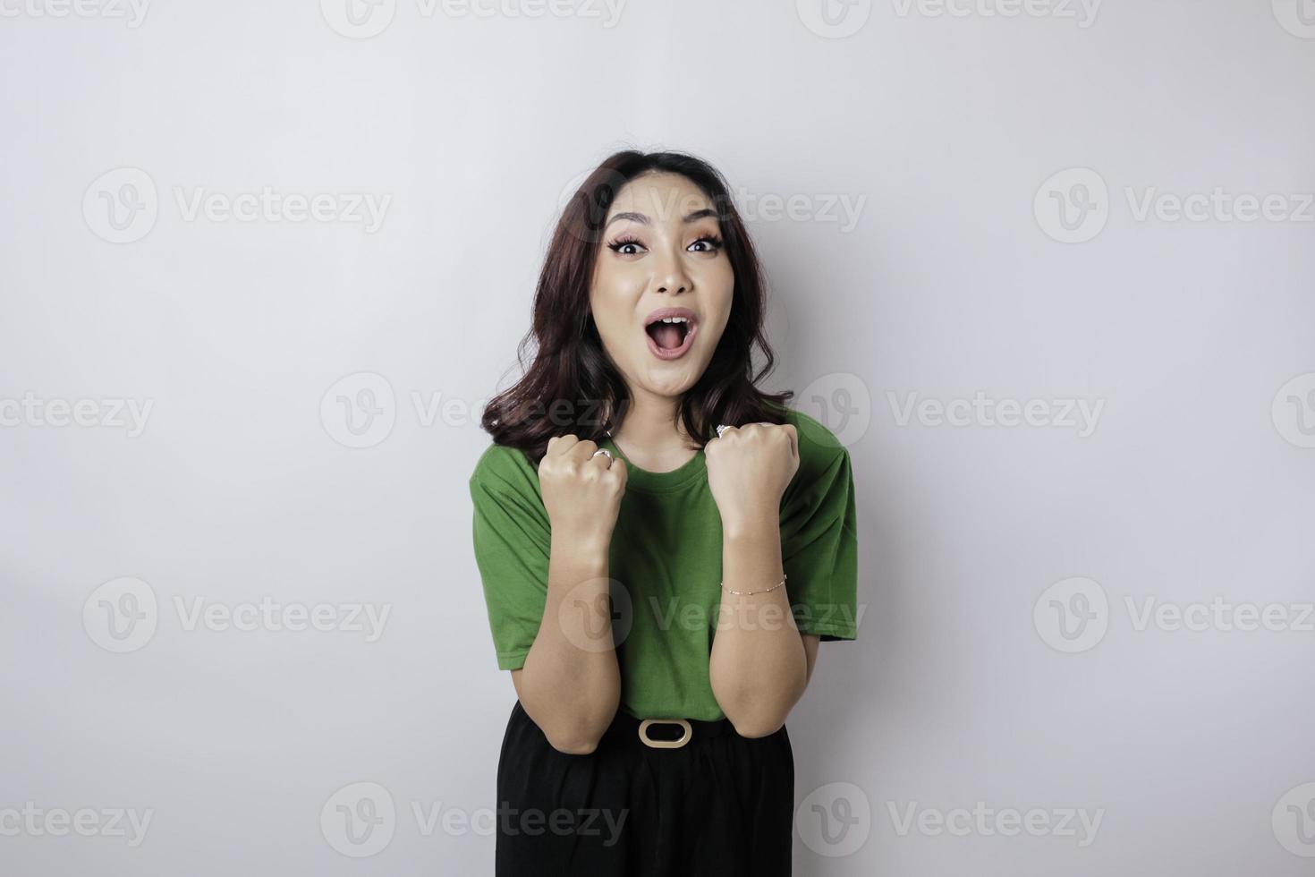 une jeune femme asiatique avec une expression heureuse et réussie portant une chemise verte isolée par fond blanc photo