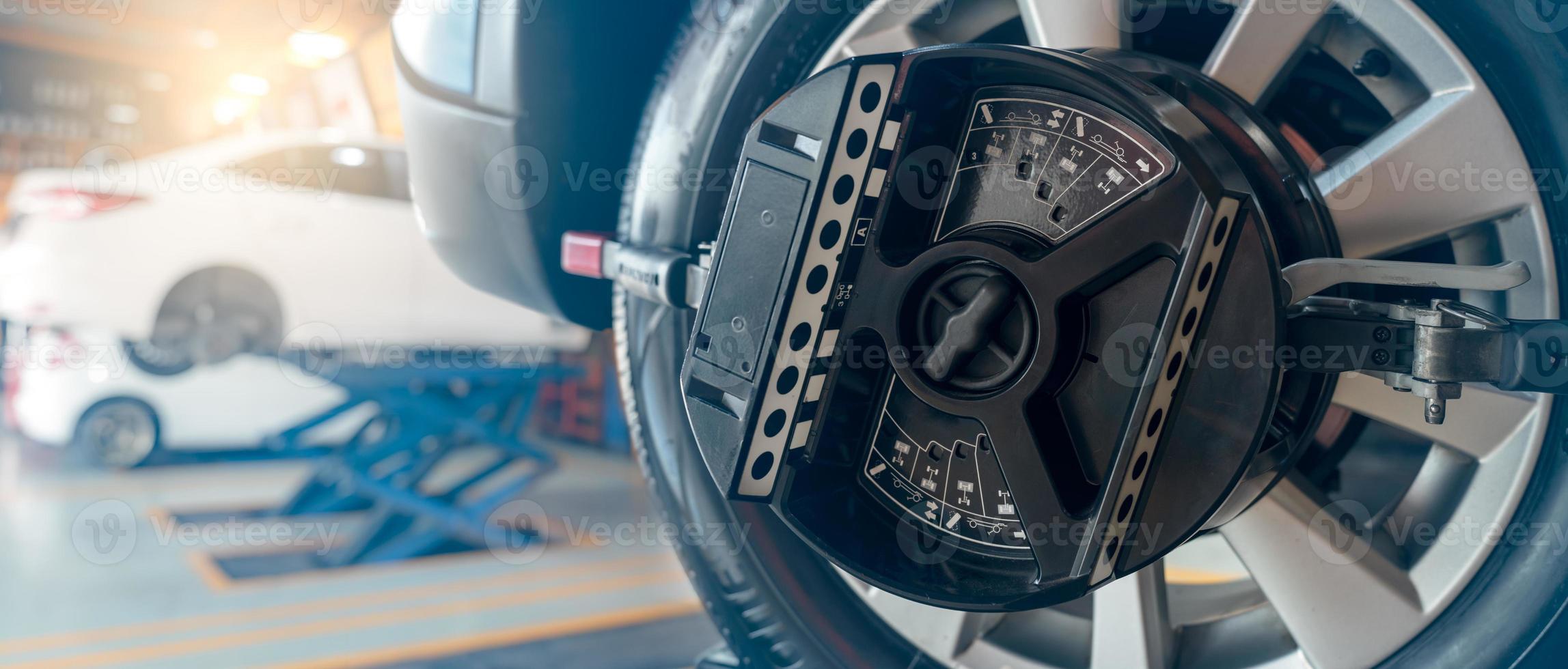 l'équipement d'alignement des roues agrippe le pneu de la roue de la voiture dans l'atelier de réparation automobile. alignement automatique des roues dans l'atelier de la station-service. équilibre de roue de voiture. réglage des suspensions. véhicule à l'intérieur du garage atelier. photo