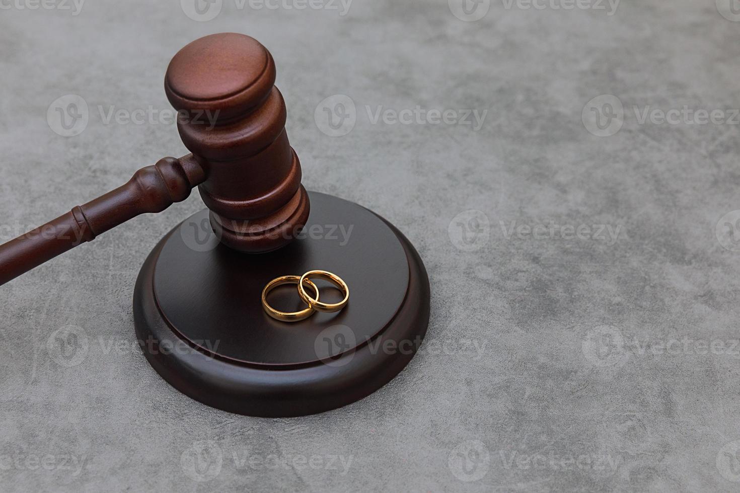 thème du droit. juges marteau anneaux de mariage sur fond gris pierre béton. procédure de divorce. maillet de juge statuant sur le mariage, le divorce, l'accord matrimonial, la légalité du divorce. photo