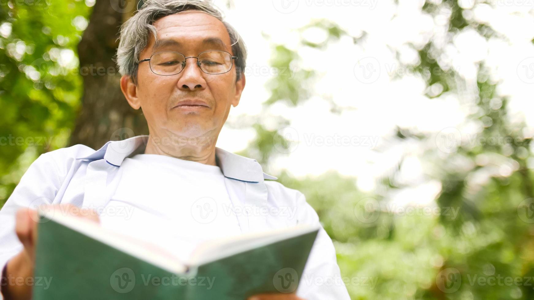 heureux homme asiatique lisant un livre dans le parc. photo