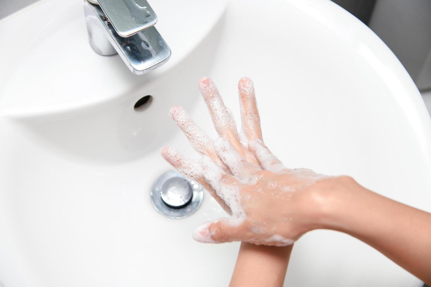 la femme utilise du savon et se lave les mains sous le robinet d'eau. photo