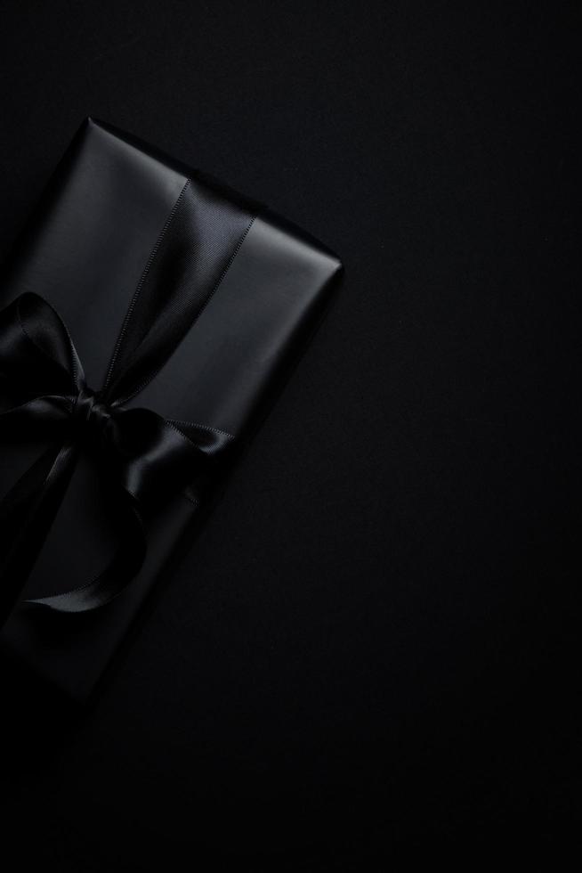vue de dessus d'une boîte cadeau noire avec des rubans noirs isolés sur fond noir. photo