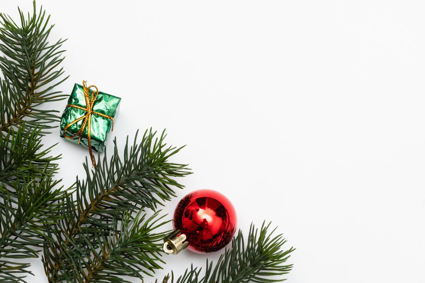 vue de dessus des boules rouges de boîte-cadeau de noël avec des branches d'épinette, des pommes de pin, des baies rouges et une cloche sur fond blanc. photo