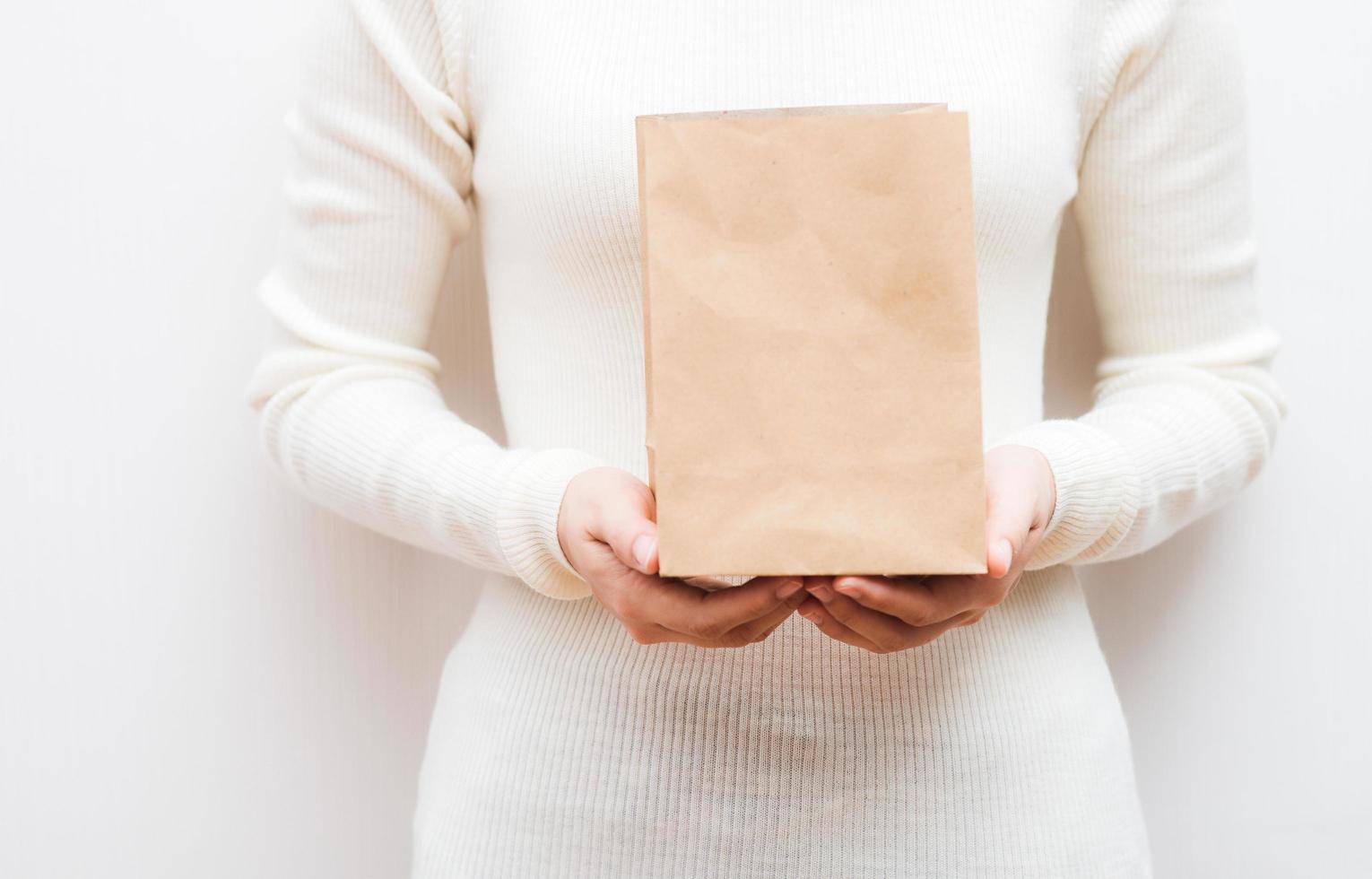 gros plan femme tient dans la main un sac en papier écologique blanc clair et vide sur fond blanc. photo