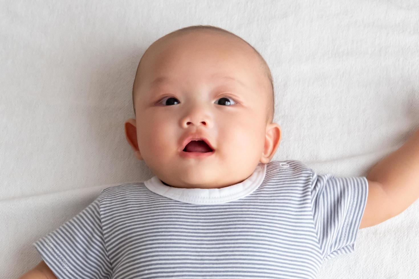 bébé souriant avec la bouche ouverte sur le matelas blanc photo