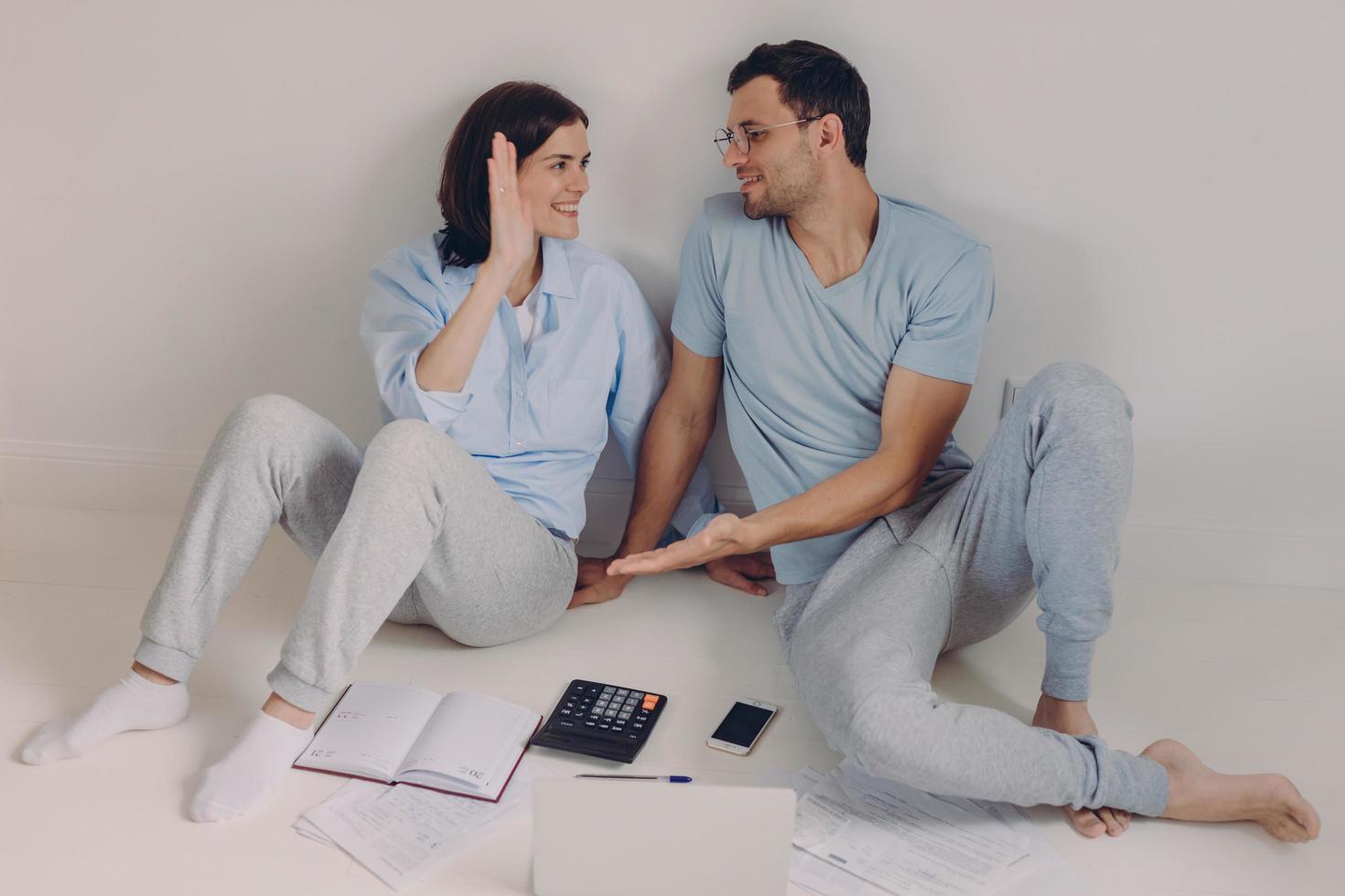 concept de personnes et d'accord. une femme et un homme heureux et satisfaits applaudissent, se regardent joyeusement, sont une équipe de travailleurs qui réussit, analysent la documentation, calculent les finances, isolés sur blanc photo